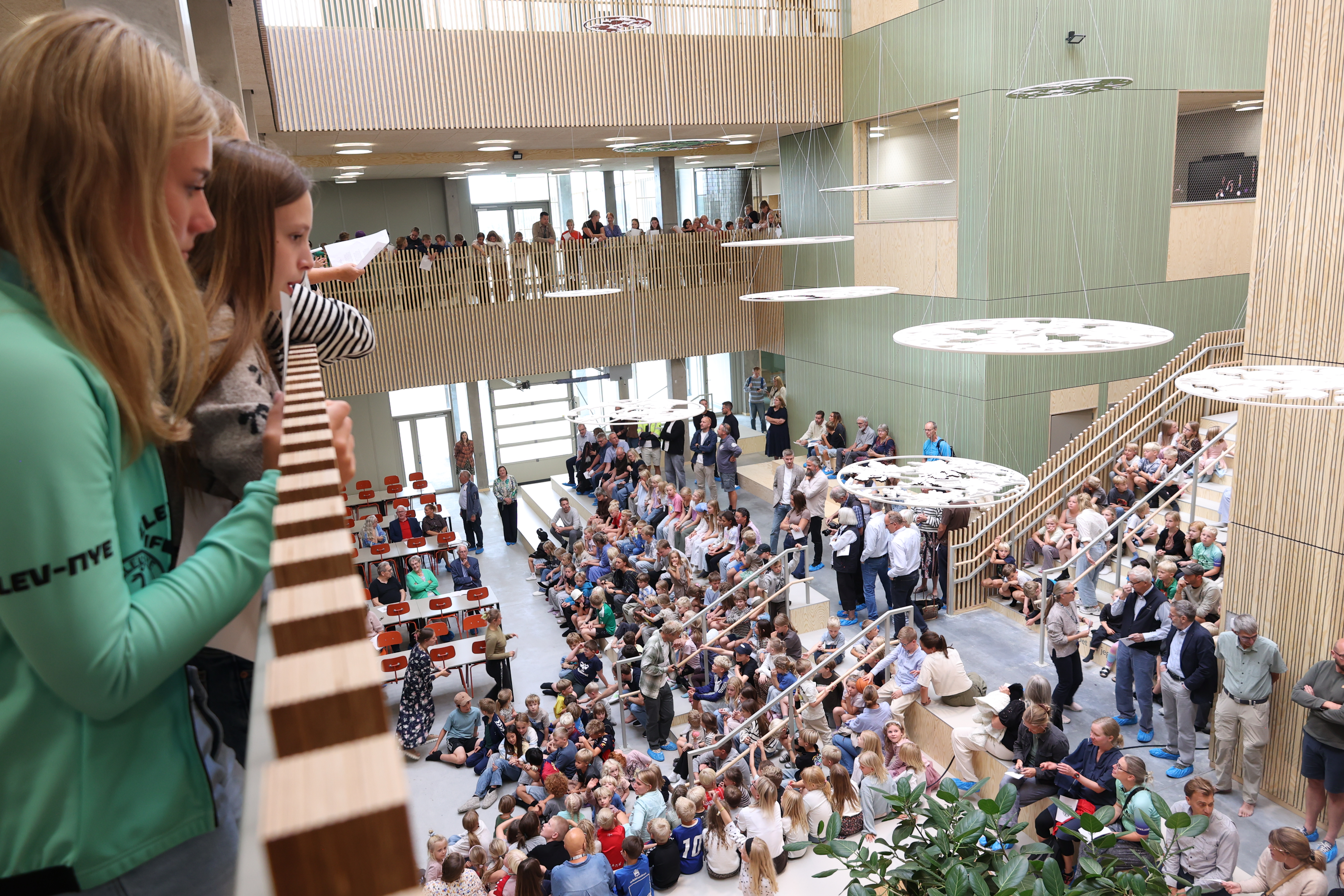En gruppe børn ser ned på andre børn og voksne til åbningen af Ravnbakkeskolen